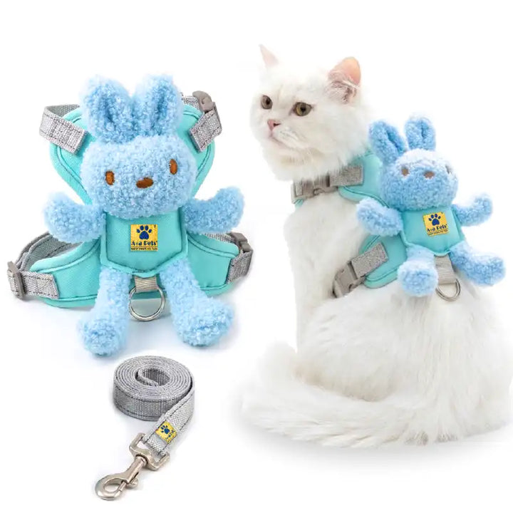 A pet harness set shown on a white cat and as a standalone product. The set includes a light blue plush bunny attachment, a mint green harness, gray straps, and a matching gray leash.