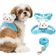 A small Shih Tzu dog wearing a light blue harness with a plush bear face attachment, shown beside the harness laid flat and a matching blue leash on a white background.