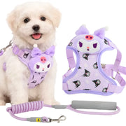 A small white puppy wearing a lavender and black Kuromi-themed harness, shown alongside the matching harness and leash laid out on a white background.