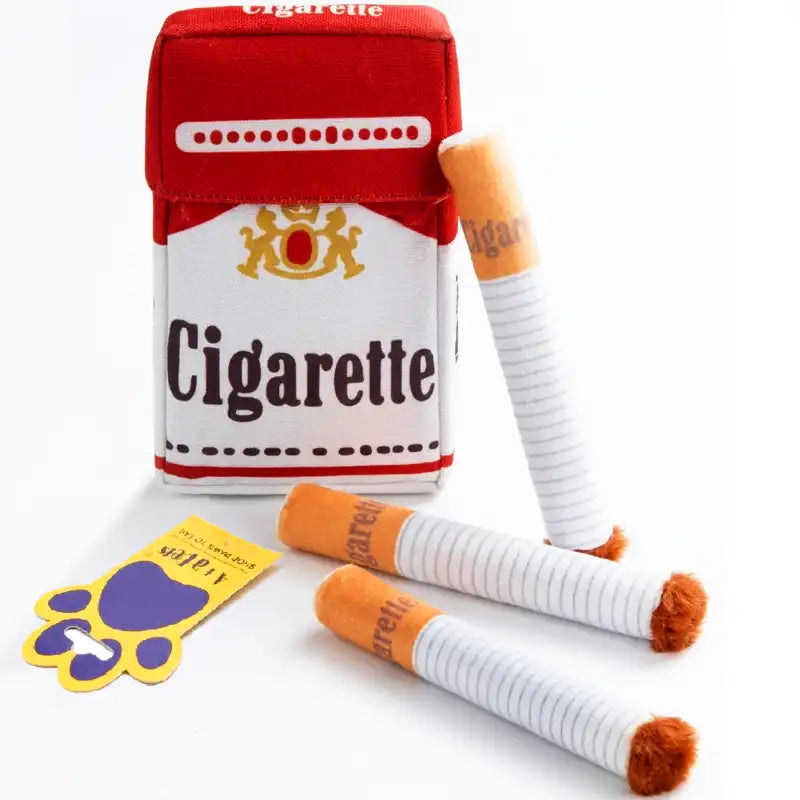 A novelty plush dog toy designed to look like a cigarette pack and three mini cigarette-shaped toys, with a yellow paw-shaped tag, set against a plain white background.