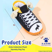 A plush dog toy shaped like a sneaker, shown with overlaid size measurements and branding text. The toy is mostly black with white laces and a white toe area, yellow collar lining, and an orange sole.