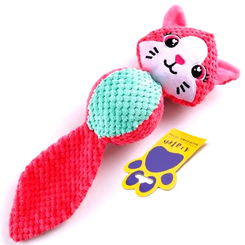 A pink and mint green crocheted cat-shaped dog toy with a yellow paw-print tag, shown on a plain white background.