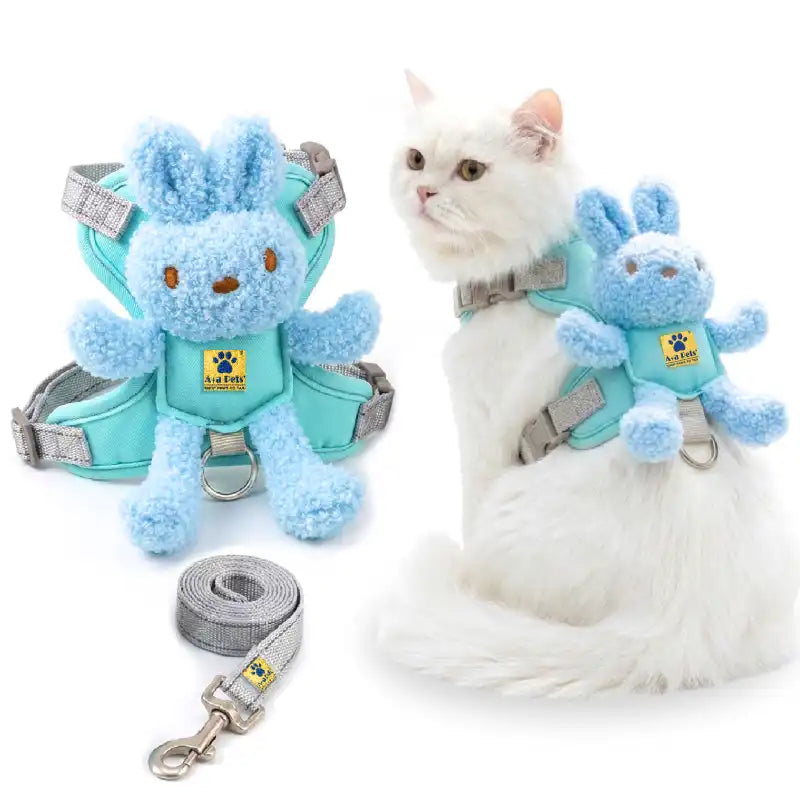 A pet harness set shown on a white cat and as a standalone product. The set includes a light blue plush bunny attachment, a mint green harness, gray straps, and a matching gray leash.