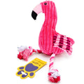 A pink plush flamingo dog toy with a striped body, pink and black beak, and rope-tail ends, shown on a white background with a yellow paw-shaped tag.