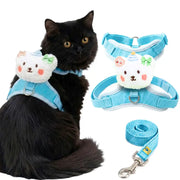 A black cat wearing a light blue pet harness with a white plush bear face attachment, shown alongside the same harness and matching leash on a white background.