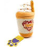 A plush dog toy shaped like a pumpkin spice latte cup, with cream-colored faux whipped cream, orange-brown cup lining, and embroidered red and yellow 'Pumpkin Spice Life is Good' text. A yellow and purple tag is placed in front on a white background.