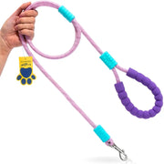 A pink rope dog leash with a purple padded handle and turquoise accents, held by a hand on a white background. A yellow paw-shaped tag is attached to the leash.