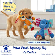 A golden retriever puppy carries a plush squeaky toy shaped like a bunny while standing on a light carpet in a room. The puppy is next to a blue elephant plush toy.