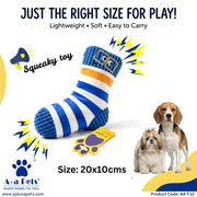 A blue and white striped squeaky dog toy shaped like a sock, shown on a white background with promotional text, cartoon sound effects, a paw print graphic, and two dogs at the right. The tag reads 'Squeaky toy' and 'Size: 20x10cms'.